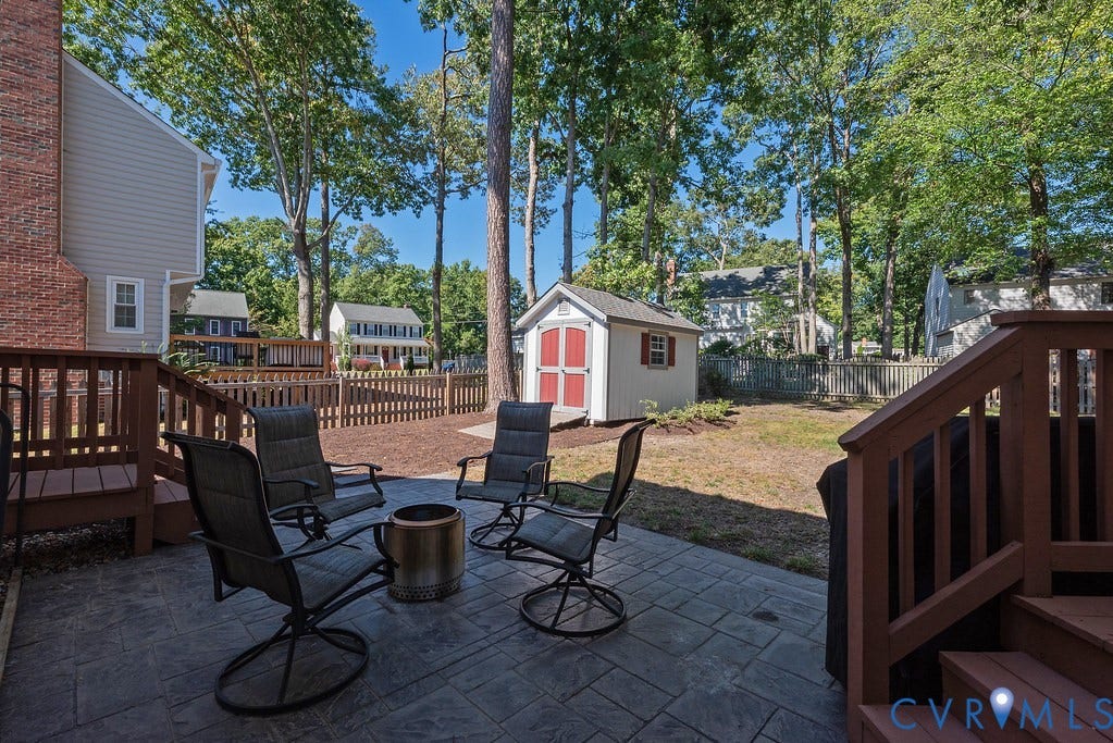Expansive backyard featuring a stamped concrete patio, privacy fencing, and a storage shed