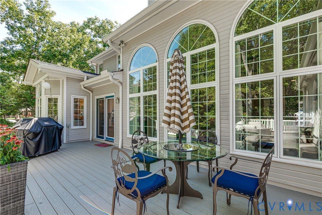 Expansive outdoor deck with composite decking, multiple arched windows, and a sliding glass door