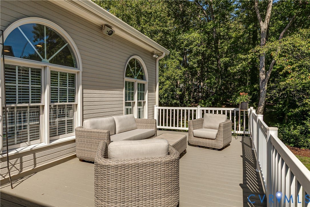 Wood-finish deck with white railing, featuring arched windows and horizontal siding
