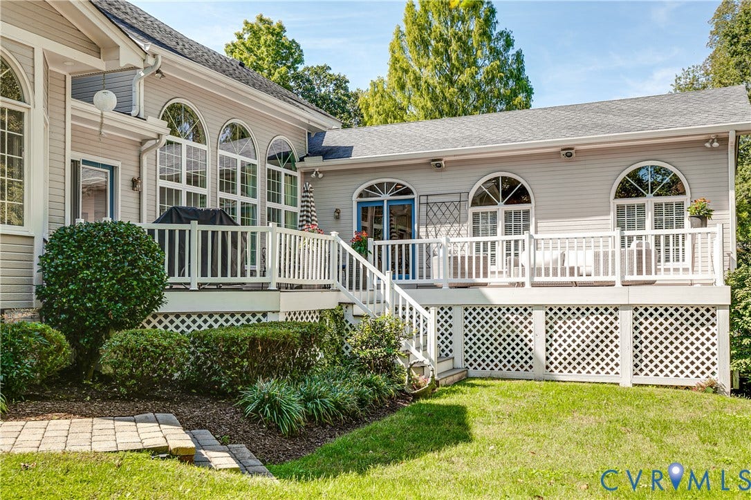 Expansive outdoor deck with white railing, lattice skirting, and multiple arched windows