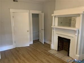 3119-A 4th Avenue, Richmond, VA 23222 Wood-finish flooring, white trim, and a fireplace with a brick interior and tile hearth
