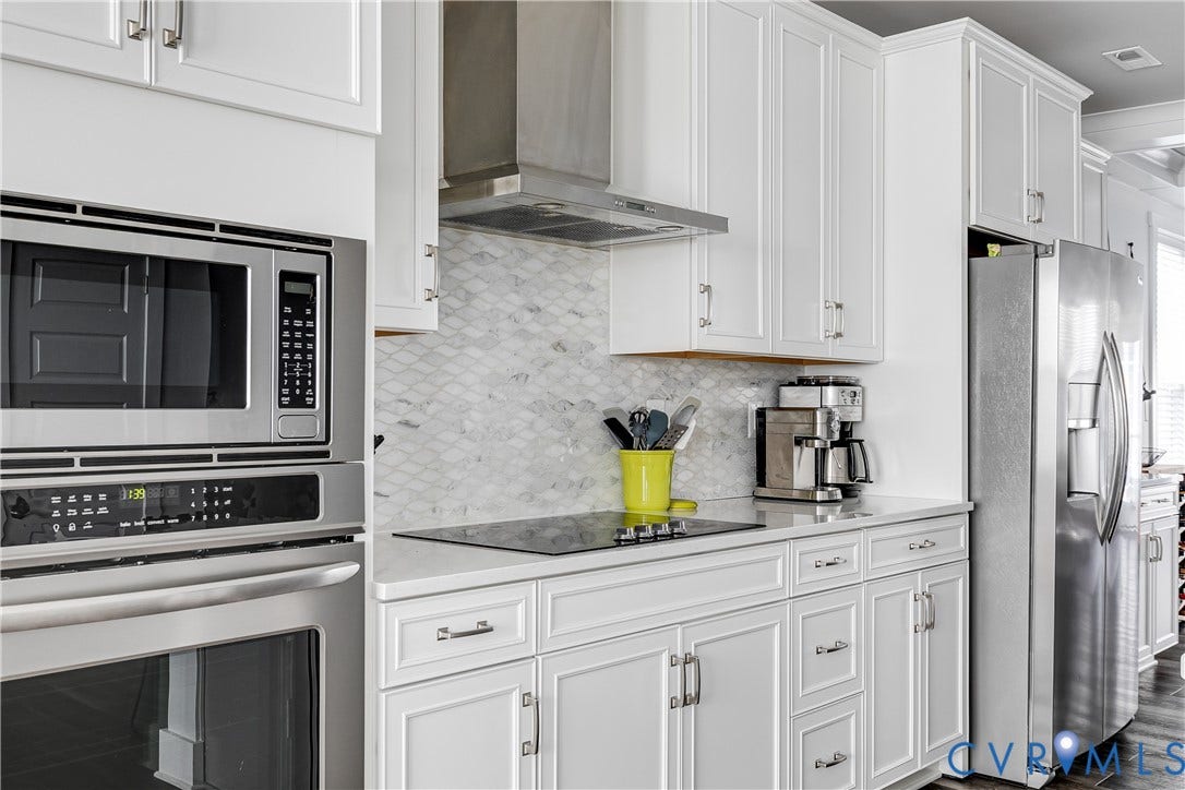 2 Flatwater Row, #B, Rocketts Landing, Henrico, VA 23231 White shaker cabinetry, stainless steel appliances, built-in microwave, integrated cooktop, and patterned tile backsplash