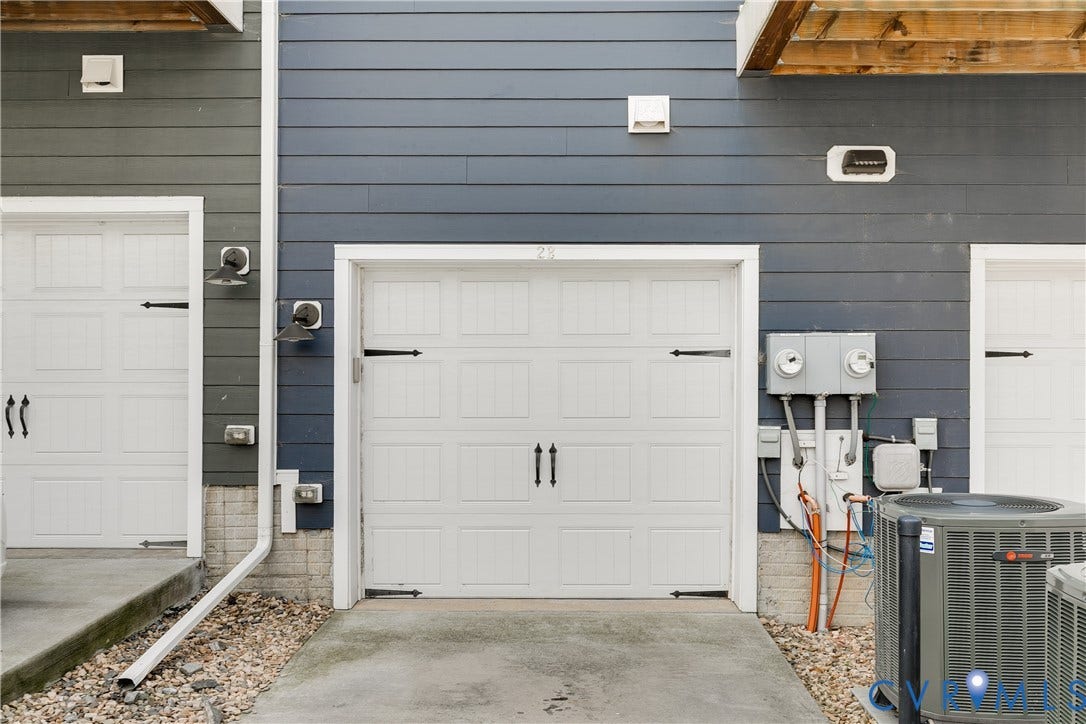 2 Flatwater Row, #B, Rocketts Landing, Henrico, VA 23231 White panel garage doors with decorative black hardware, framed by dark blue siding