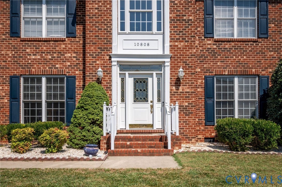 10808 Pruett Lane, Henrico, VA 23059 Brick exterior with white trim, a decorative front door with leaded glass, and white porch railings