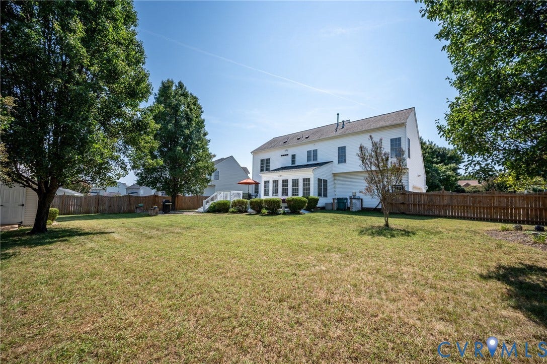 10808 Pruett Lane, Henrico, VA 23059 Expansive fenced backyard with a white two-story dwelling, mature trees, and a wooden storage shed