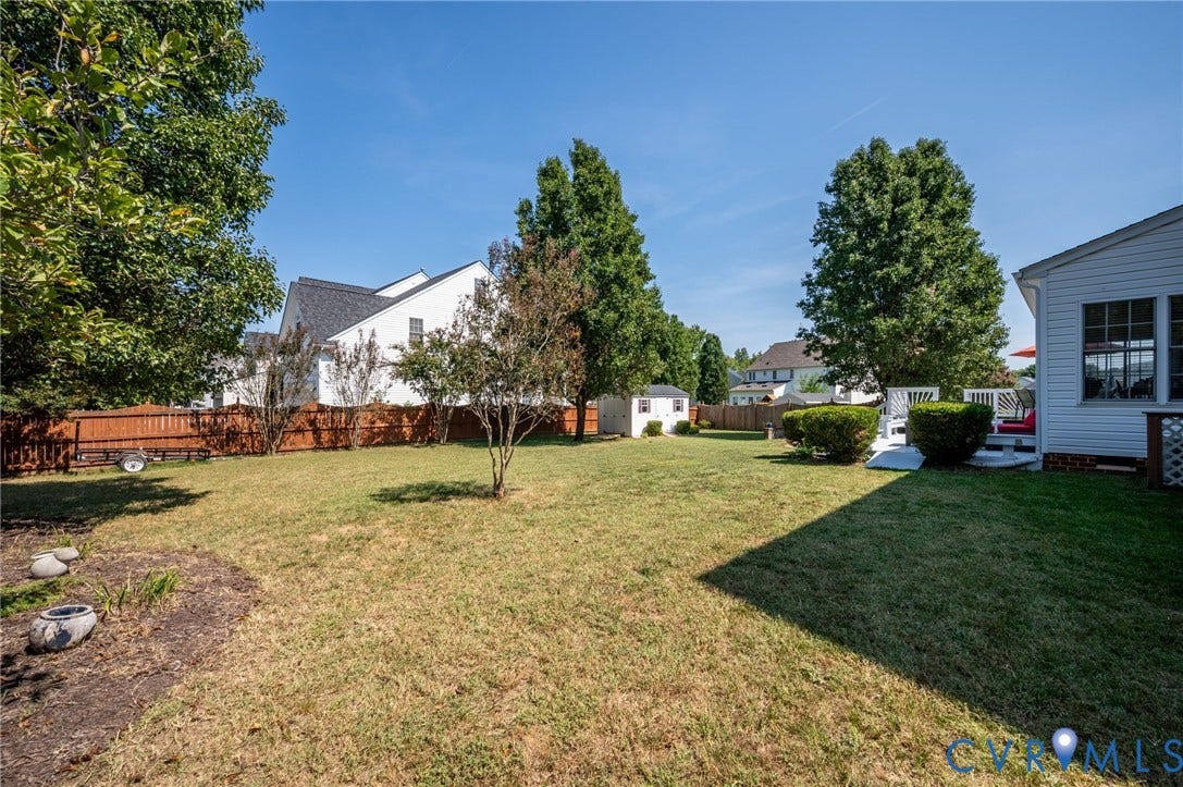 10808 Pruett Lane, Henrico, VA 23059 Expansive lawn with mature trees, privacy fencing, a white storage shed, and a composite deck with white railings