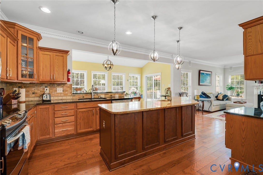 10808 Pruett Lane, Henrico, VA 23059 Hardwood flooring throughout, kitchen featuring wood cabinetry and dark countertops, central island with lighter countertop, recessed lighting, and multiple pendant light fixtures