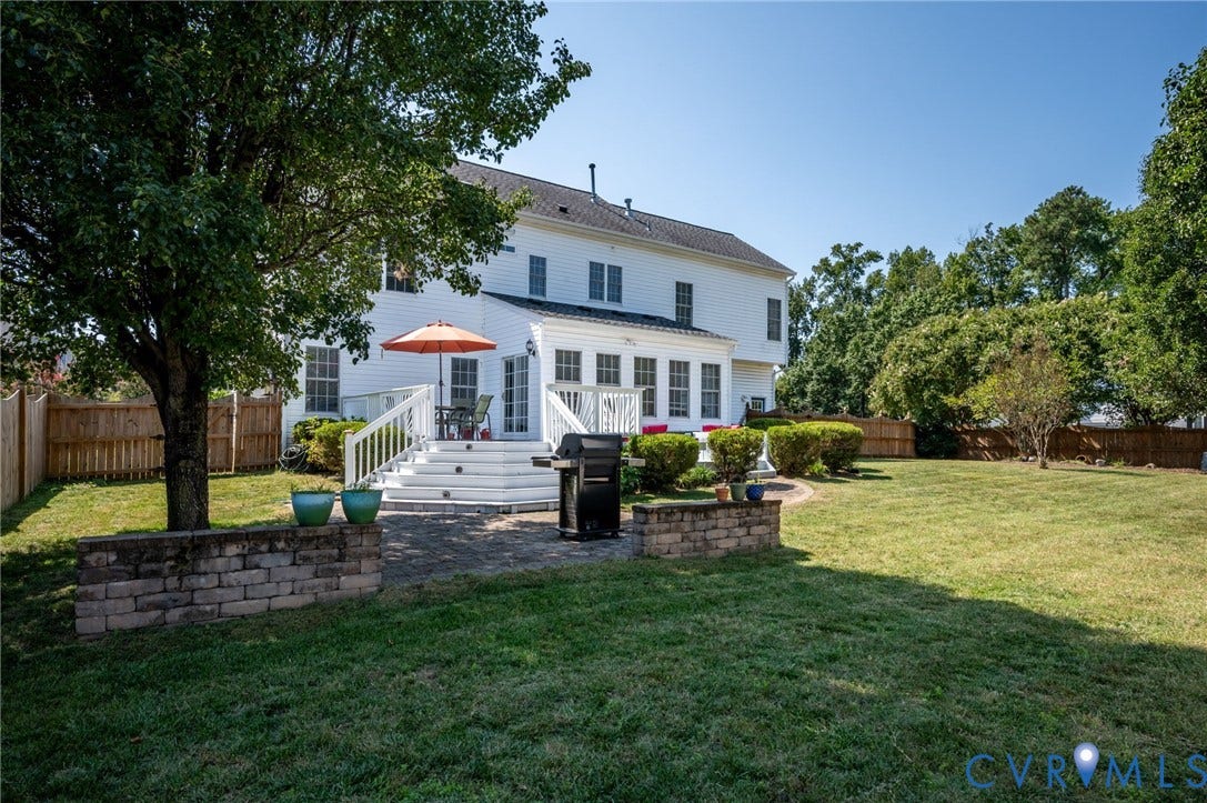 10808 Pruett Lane, Henrico, VA 23059 Rear exterior featuring a white multi-story residence, a multi-level white deck, a stone retaining wall, and a wood privacy fence
