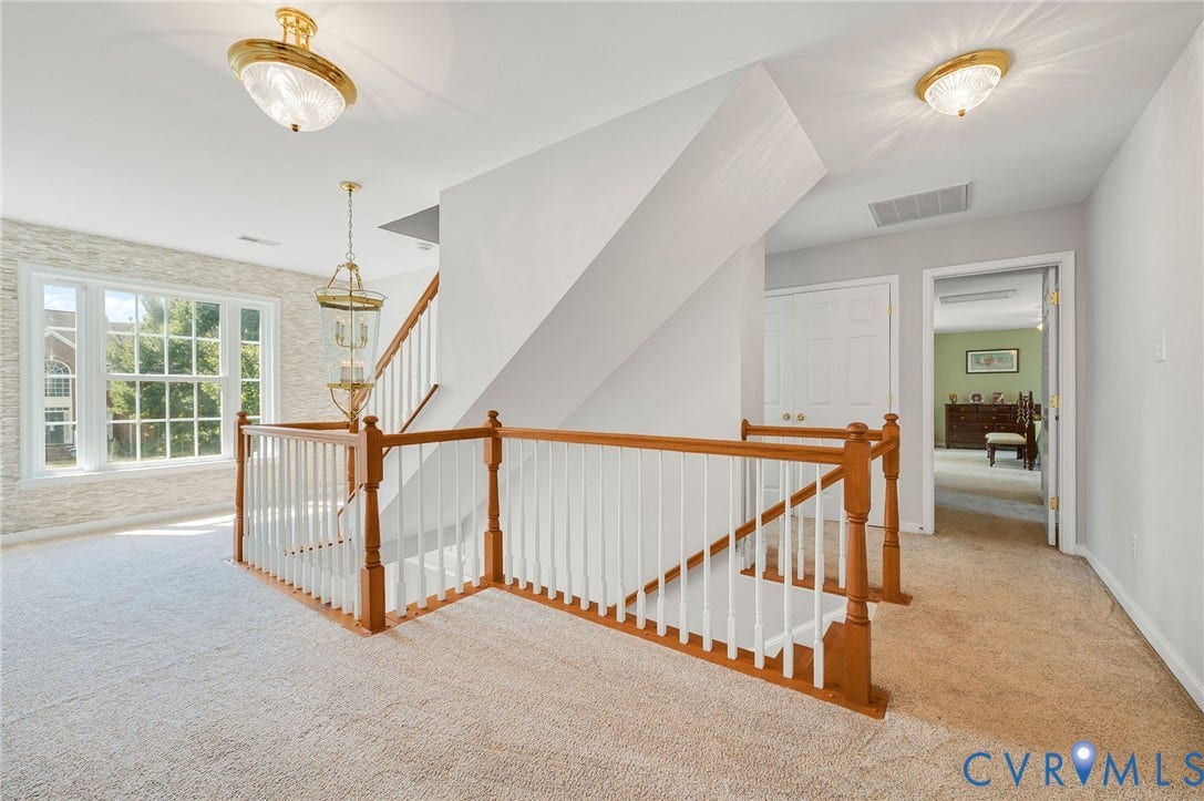 10808 Pruett Lane, Henrico, VA 23059 Spacious upper-level landing featuring hardwood railings with white spindle detailing, neutral carpet flooring, and abundant natural light from multi-pane windows