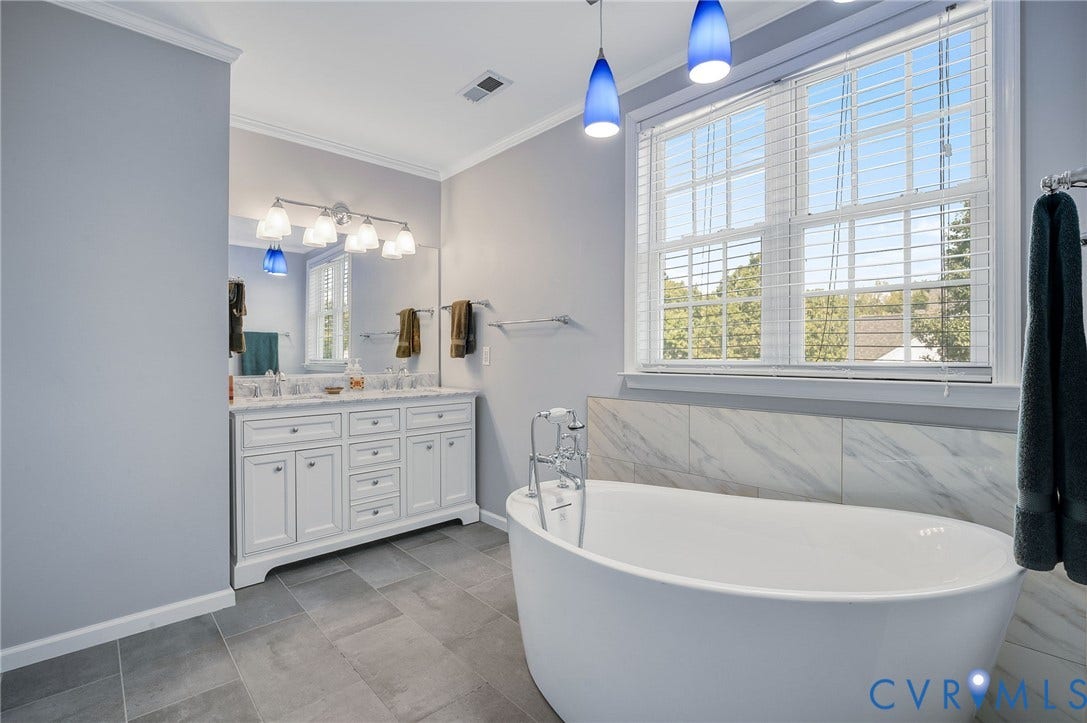 10808 Pruett Lane, Henrico, VA 23059 Freestanding soaking tub with a wall-mounted faucet, double vanity with stone countertop, large window with blinds, and tile flooring