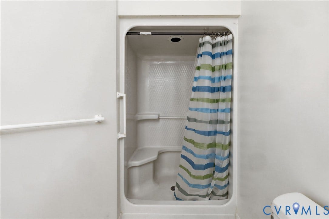 Master bathroom with white shower stall with an integrated seat and grab bar