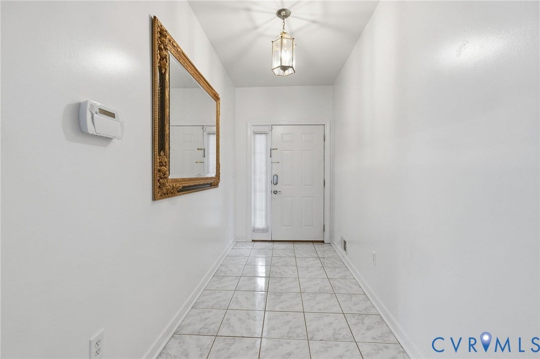 Recessed entryway featuring a tiled floor, white walls, and a decorative ceiling light fixture