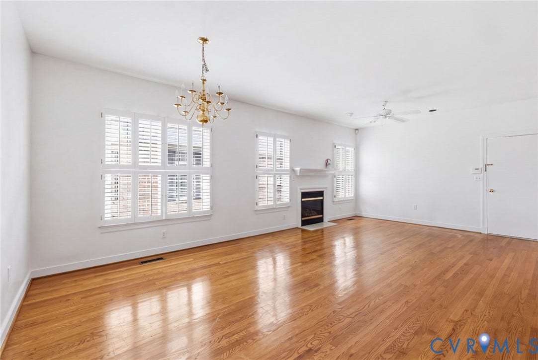 Hardwood flooring, white walls, and a fireplace with a mantel