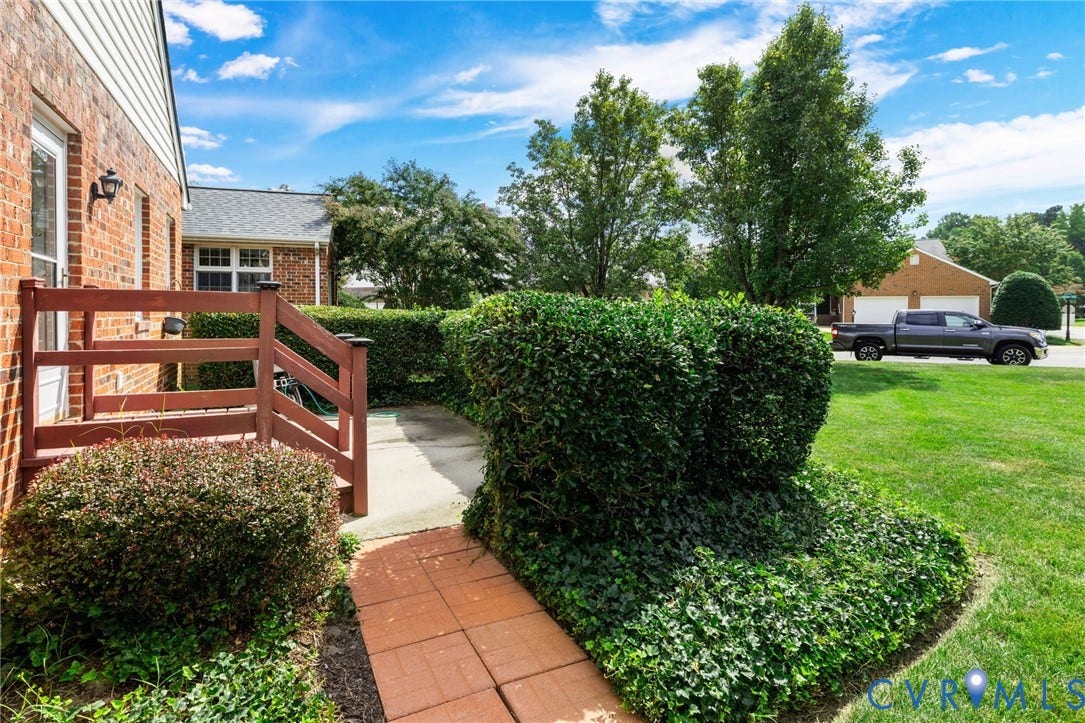 Brick exterior with white siding accents and a wood-finish railing