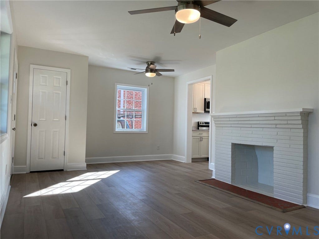2315 Dee Kay Drive, Henrico, VA 23228 Spacious living area featuring wood-finish flooring, a white-painted brick fireplace, and two ceiling fans