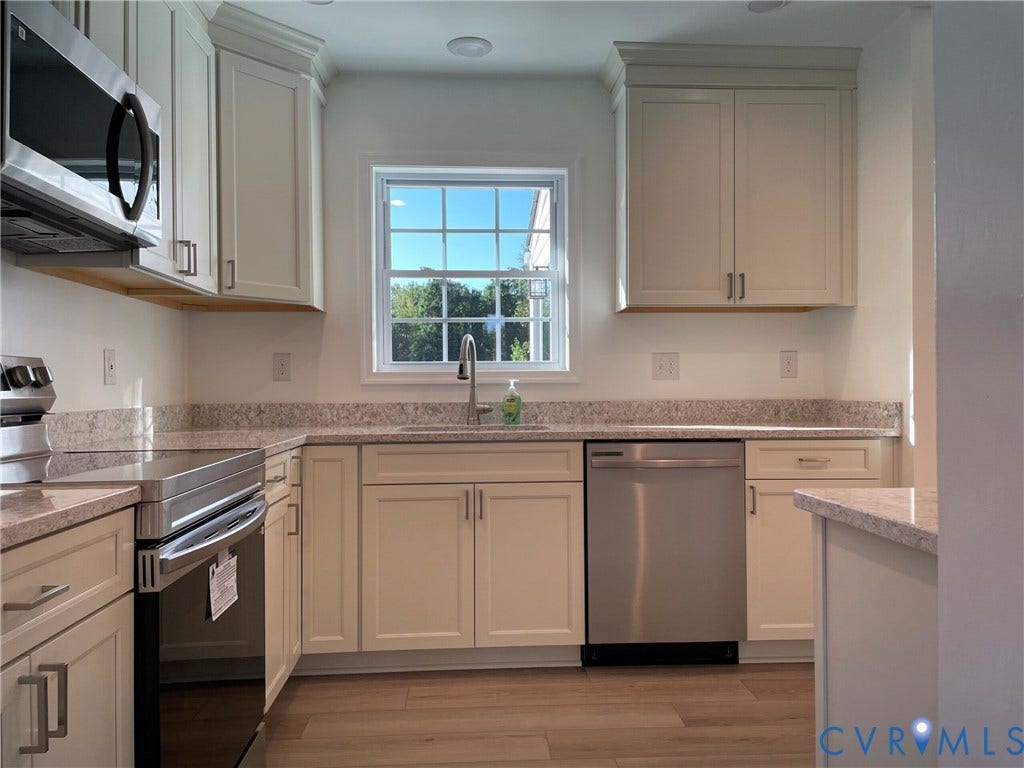 2315 Dee Kay Drive, Henrico, VA 23228 White shaker-style cabinetry with crown molding, stainless steel appliances, speckled countertops, wood-finish flooring, and an undermount sink with a gooseneck faucet