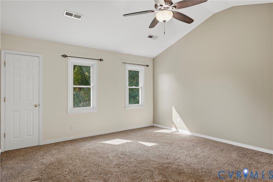 Vaulted ceiling featuring a ceiling fan with integrated lighting, neutral wall tones, and two windows