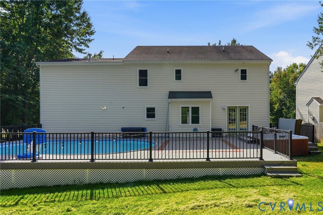 Expansive backyard featuring a fenced-in swimming pool, a tiered deck with a hot tub, and white siding