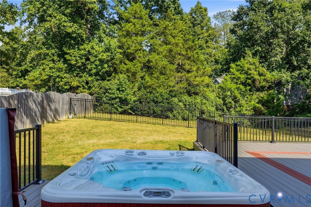 Inviting hot tub on a multi-toned composite deck, surrounded by black metal railings