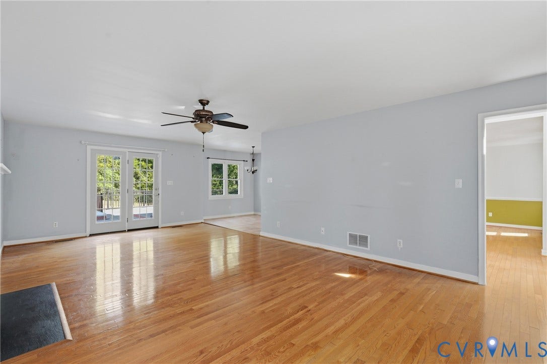 Hardwood flooring, ceiling fan, French doors, multiple windows, and light gray wall paint