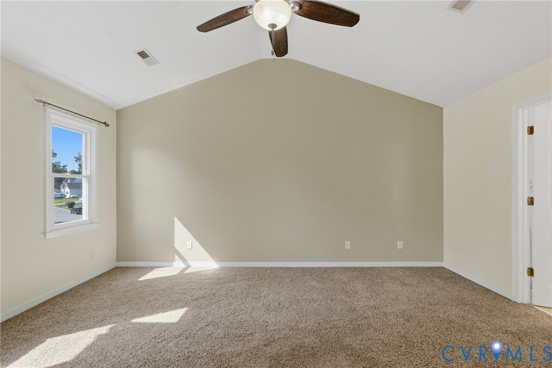 Vaulted ceiling with an integrated ceiling fan, light-toned walls, and plush carpeting
