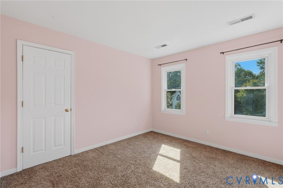 Room featuring two windows, neutral carpet, and a paneled door