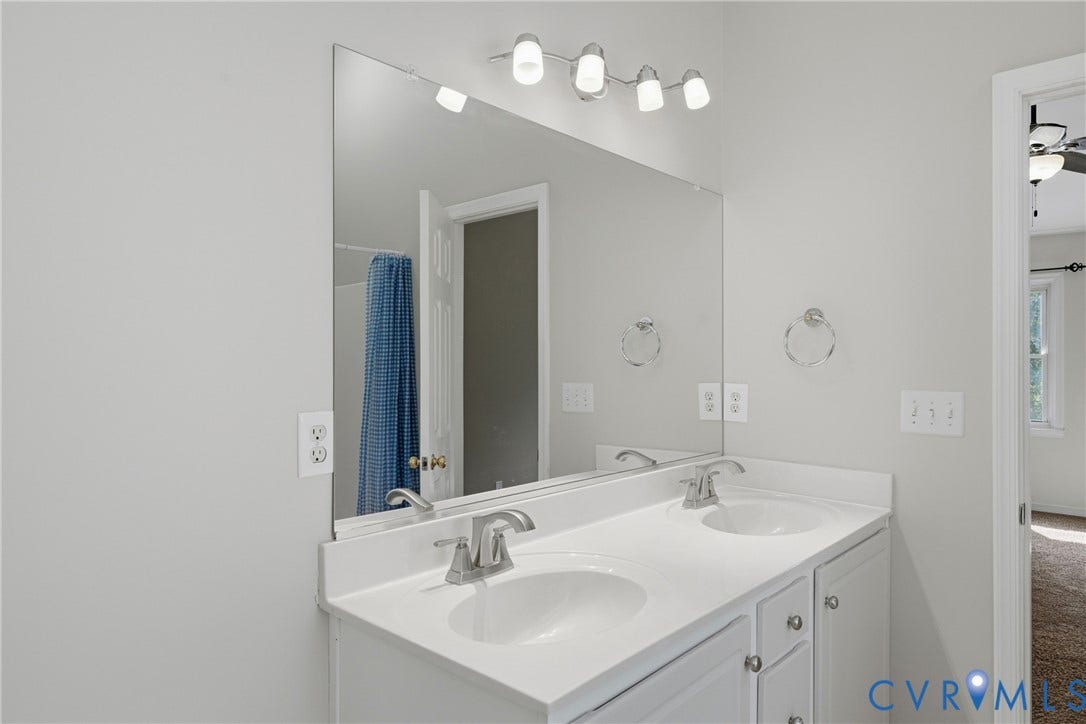Dual undermount sinks with brushed nickel faucets, set into a white countertop with integrated backsplash