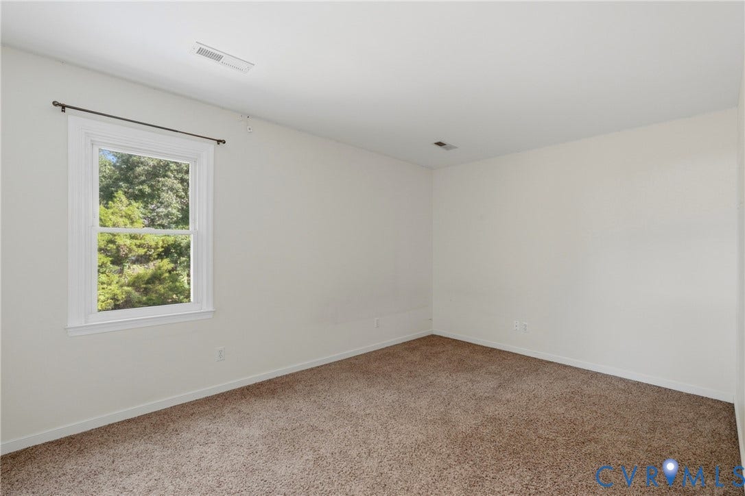 Carpeted room with white walls and a single window featuring white trim