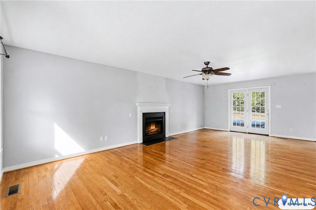 Hardwood flooring, white walls, and a fireplace with a white mantel and black surround