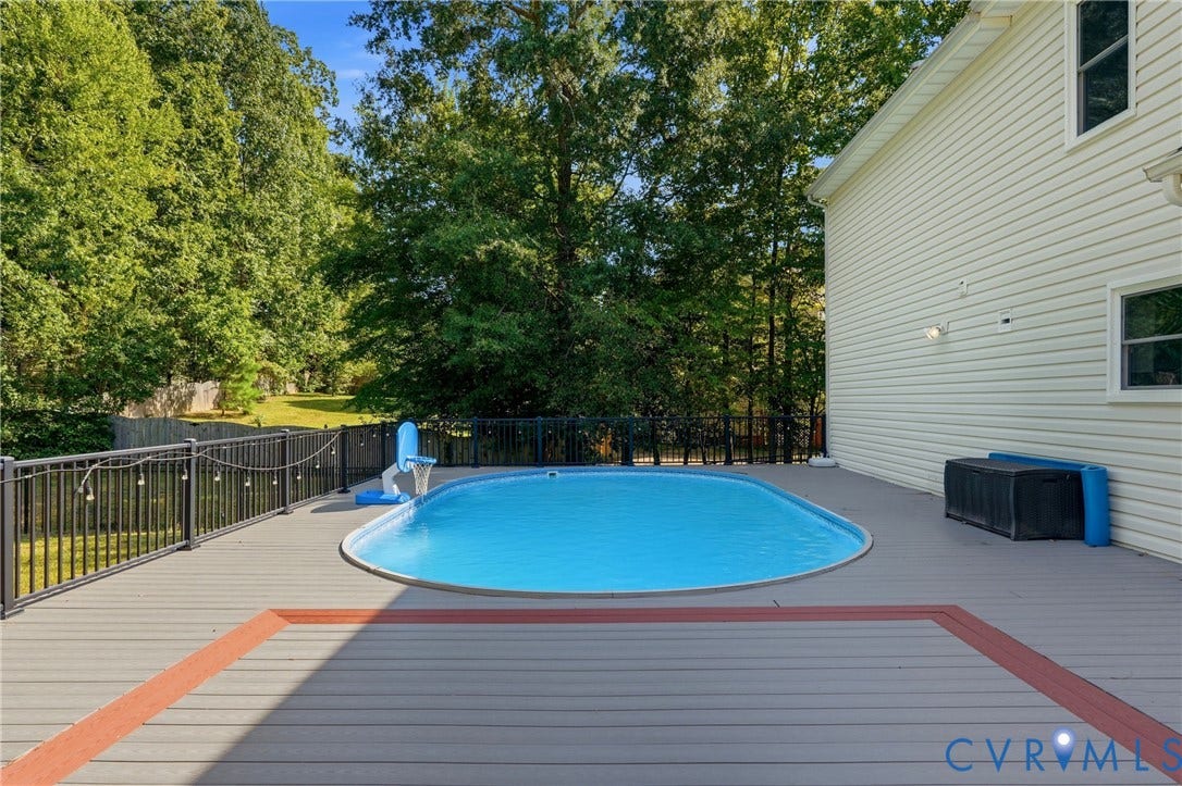 Expansive deck with an in-ground swimming pool, surrounded by a black metal fence