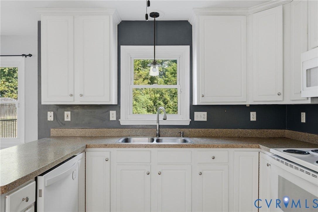 White cabinetry, L-shaped countertop, double basin sink, and a built-in dishwasher