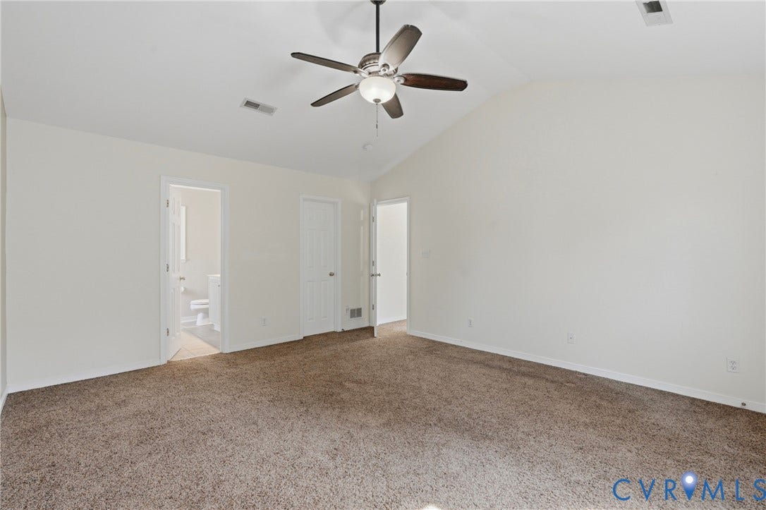 Vaulted ceiling with a ceiling fan, plush carpet, and light-toned walls