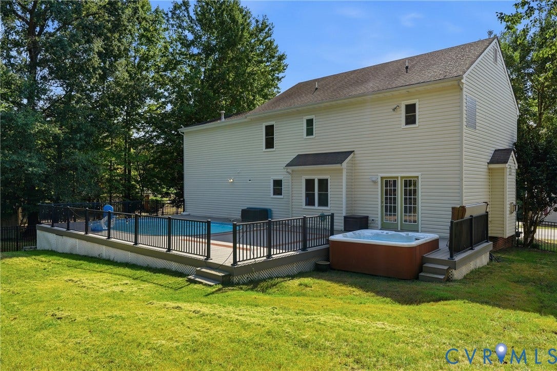 Rear exterior featuring a swimming pool, hot tub, and a multi-level deck with black railings