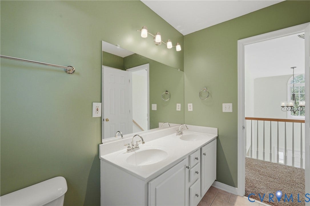Dual vanity with integrated sinks, polished chrome fixtures, and a large wall-mounted mirror