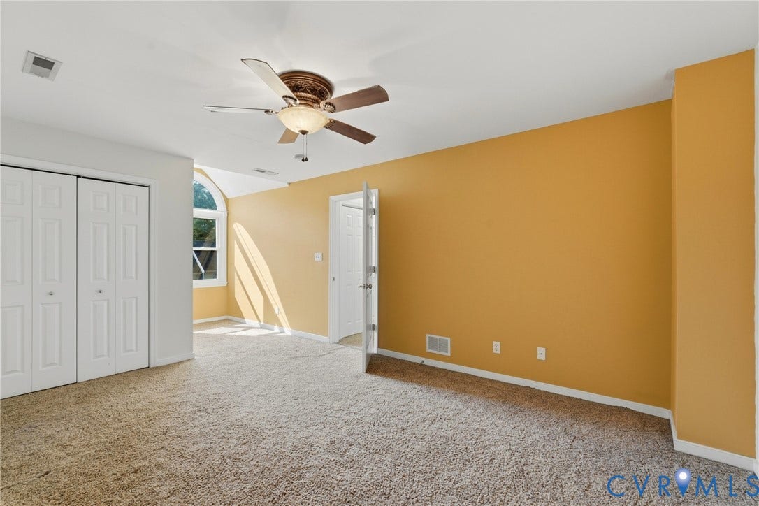Arched window, ceiling fan, bi-fold closet doors, and wall-to-wall carpeting