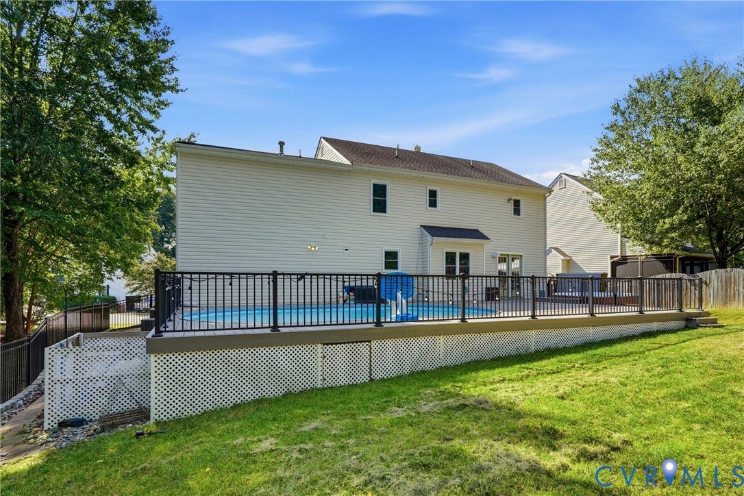 Expansive backyard featuring a large swimming pool, elevated deck with dark railings, and a sizable lawn