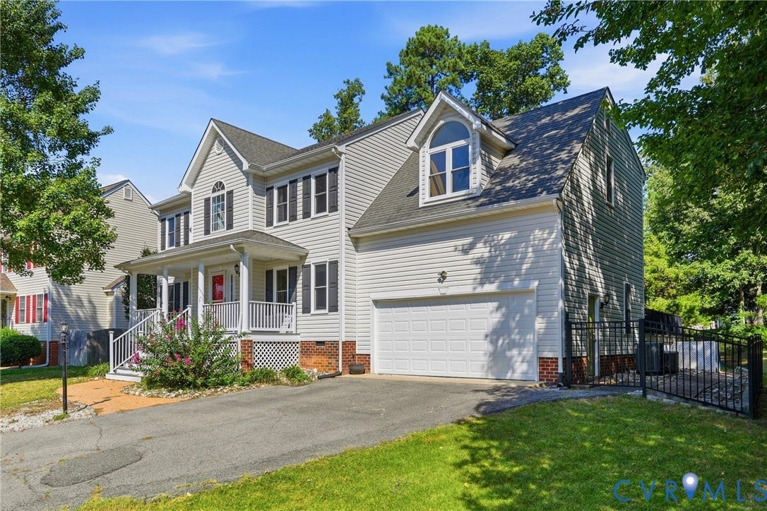 Two-story residential architecture with siding exterior, attached garage, covered front porch, and dormer window