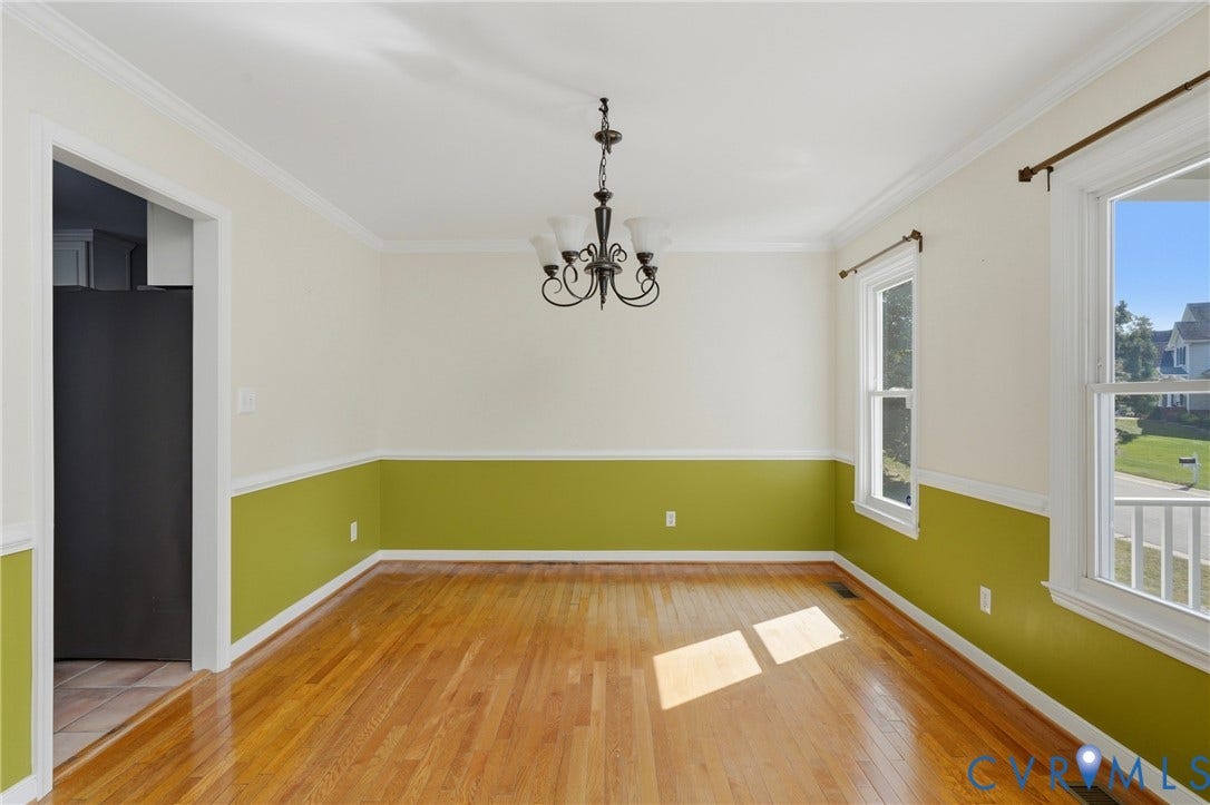 Hardwood flooring, painted walls with chair rail molding, ceiling-mounted light fixture, and multiple windows