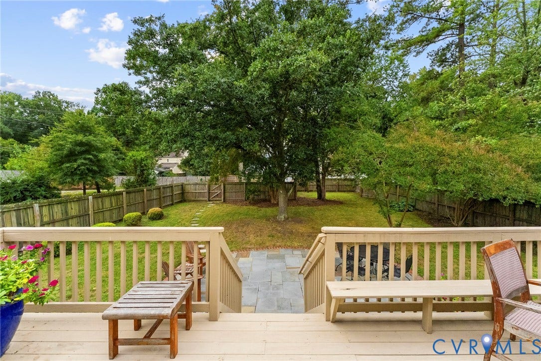 4905 Patterson Avenue, Richmond, VA 23226 Expansive backyard featuring a wood deck, stone patio, mature trees, and privacy fencing