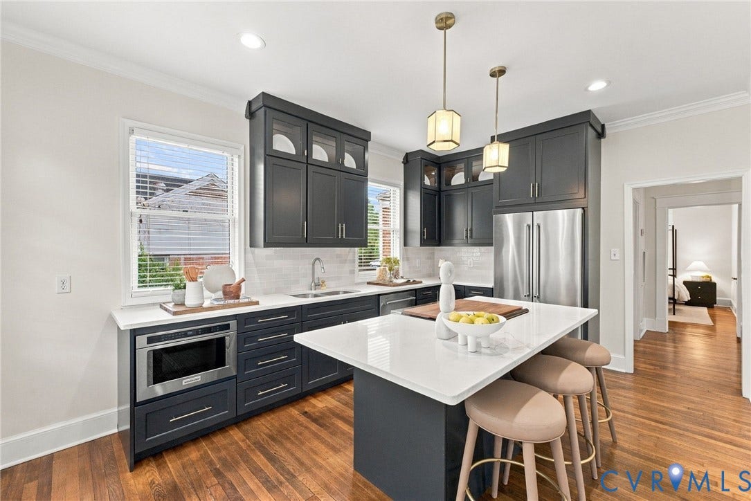 4905 Patterson Avenue, Richmond, VA 23226 Kitchen featuring dark cabinetry, stainless steel appliances, a center island with seating, a white subway tile backsplash, and wood-finish flooring