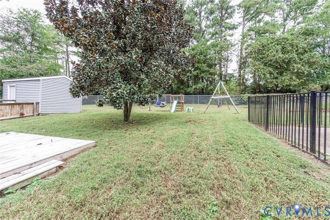 5640 Teterling Court, Lakewood Farms, Chester, VA 23831 Expansive backyard featuring a wood deck, mature trees, a storage shed, and perimeter fencing