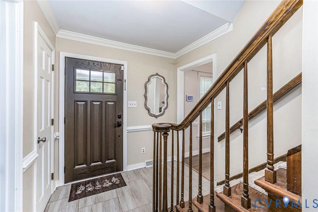 5640 Teterling Court, Lakewood Farms, Chester, VA 23831 Entryway featuring a dark paneled door with glass inserts, light wood-finish flooring, a traditional wood staircase, and crown molding