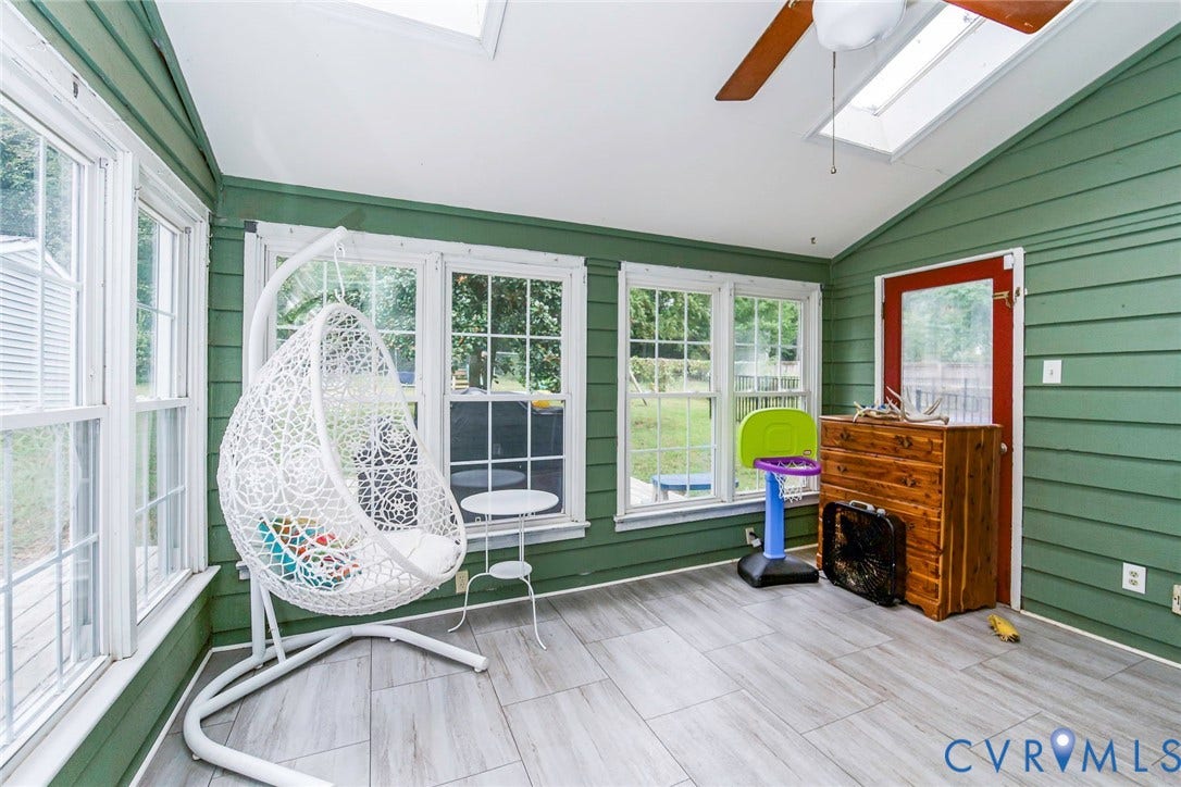 5640 Teterling Court, Lakewood Farms, Chester, VA 23831 Vaulted ceiling with dual skylights, wood-finish ceiling fan, multiple window panels, wood-finish flooring, and a red-painted door