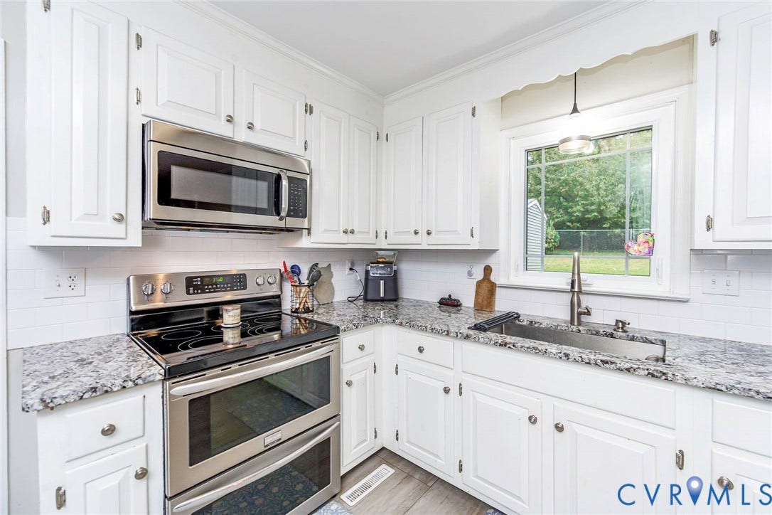 5640 Teterling Court, Lakewood Farms, Chester, VA 23831 White cabinetry with brushed nickel hardware, stainless steel appliances, speckled stone countertops, white subway tile backsplash, and a stainless steel undermount sink with a gooseneck faucet