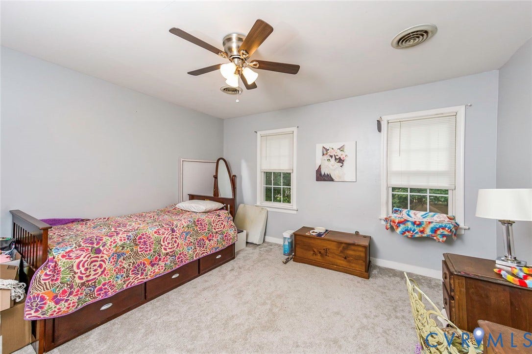 5640 Teterling Court, Lakewood Farms, Chester, VA 23831 Light gray wall paint, two windows with white trim, wood-finish ceiling fan, and gray carpet