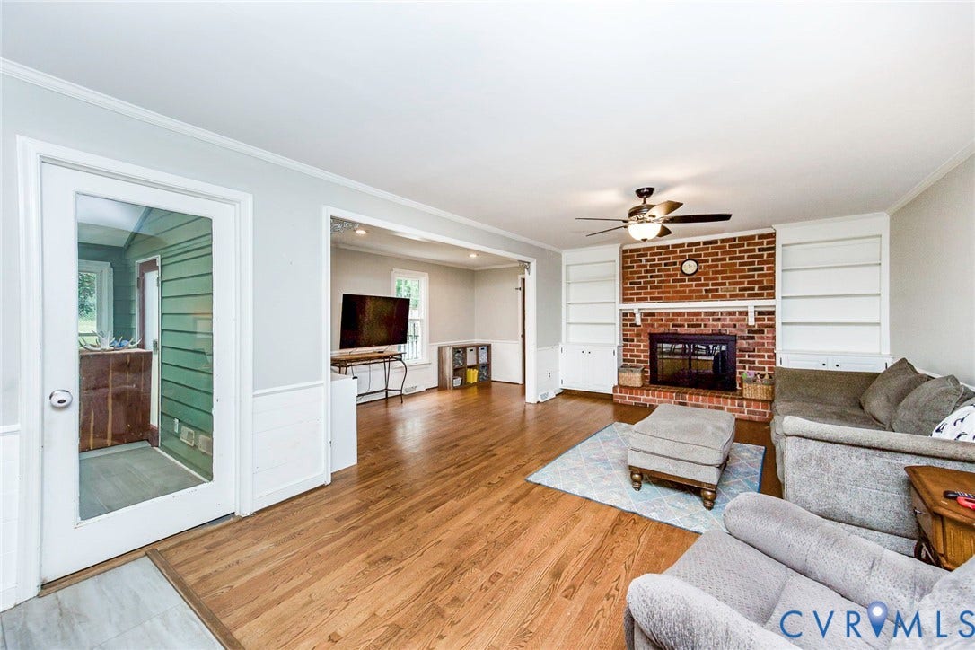 5640 Teterling Court, Lakewood Farms, Chester, VA 23831 Brick fireplace with hearth, built-in shelving, wood-finish flooring, and a ceiling fan with integrated lighting