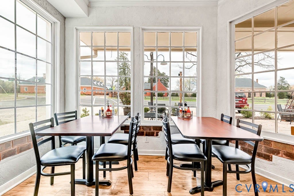 Abundant natural light through grid-patterned windows, wood-finish flooring, textured white walls, and a brick half-wall detail