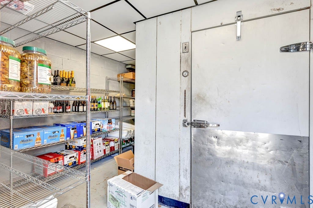 Walk-in cooler with a metal door and exterior gauge, complemented by commercial-grade wire shelving units
