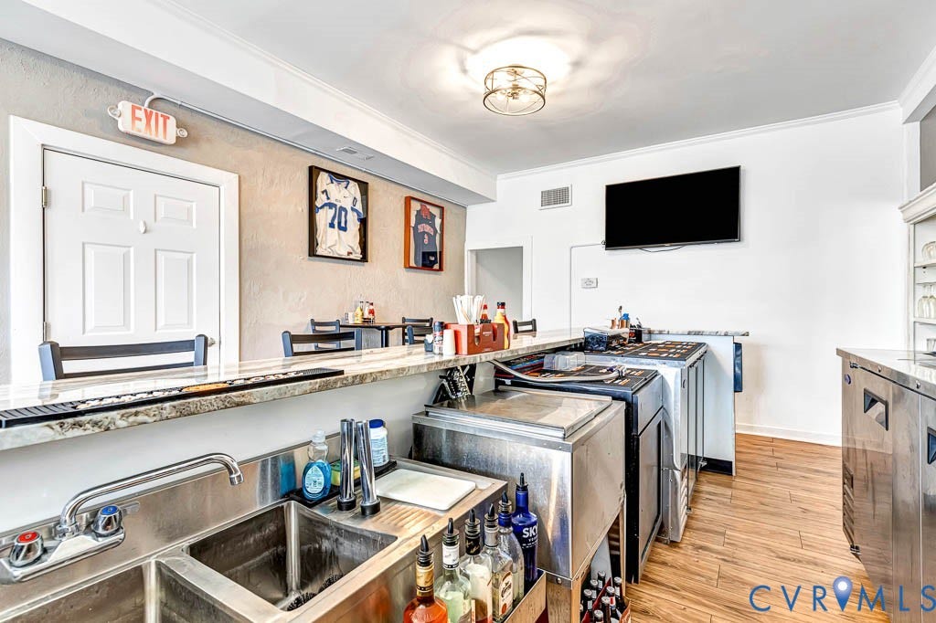 Expansive bar area featuring a stone-finish countertop, stainless steel sinks, and wood-finish flooring
