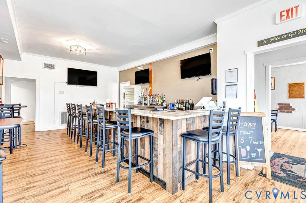 Wood-finish flooring, recessed lighting, and crown molding define this interior space
